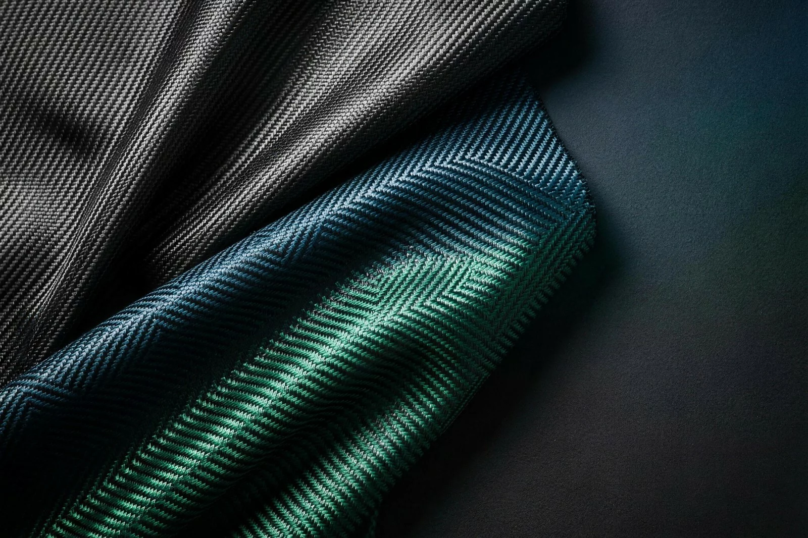 Il Tessuto Morbido nelle tre finiture: nero grafite, blu petrolio e verde, con la stessa trama di carbonio leggibile in tutte